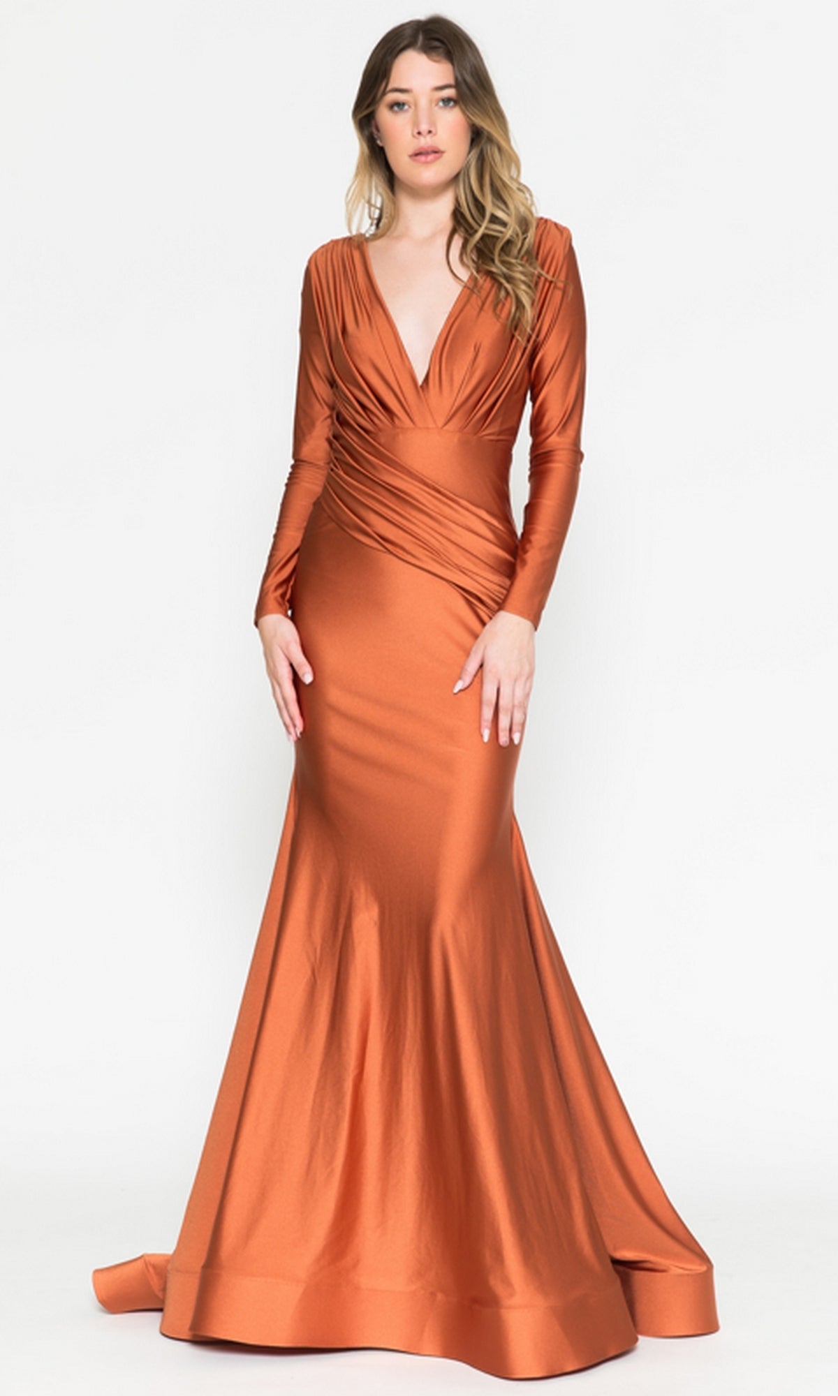 A woman models the Amelia Couture 381, a long sleeve formal dress in metallic copper with a deep V-neck, fitted ruched waist, and elegant mermaid skirt.